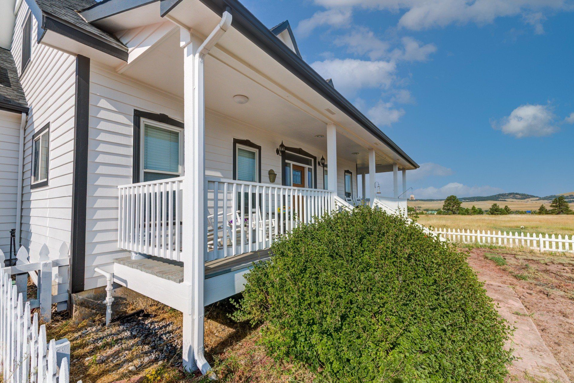 A white house with a porch and a white picket fence