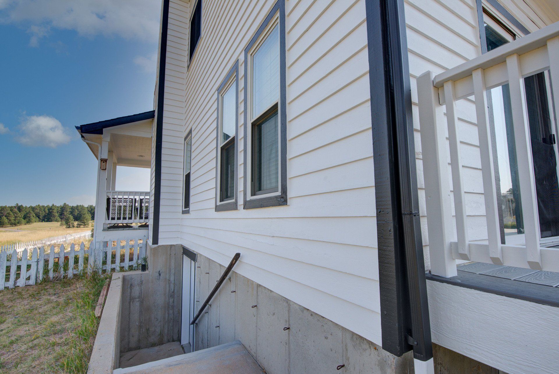 A white house with stairs leading up to the basement