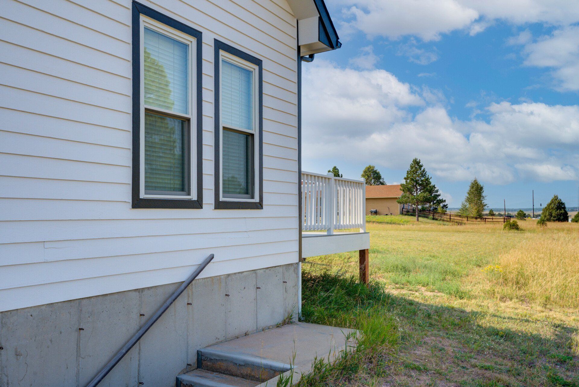 The side of a white house with stairs leading up to it.