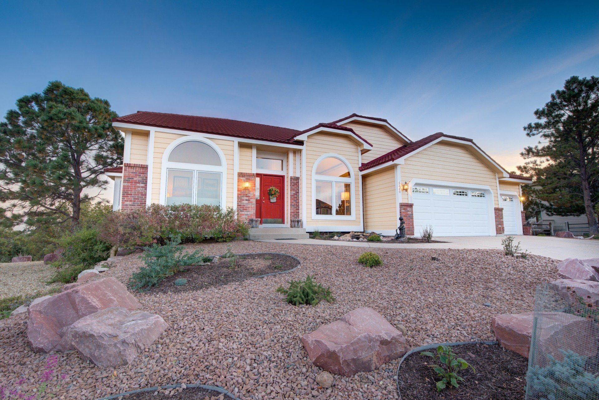 a large yellow house with a red door and a white garage door