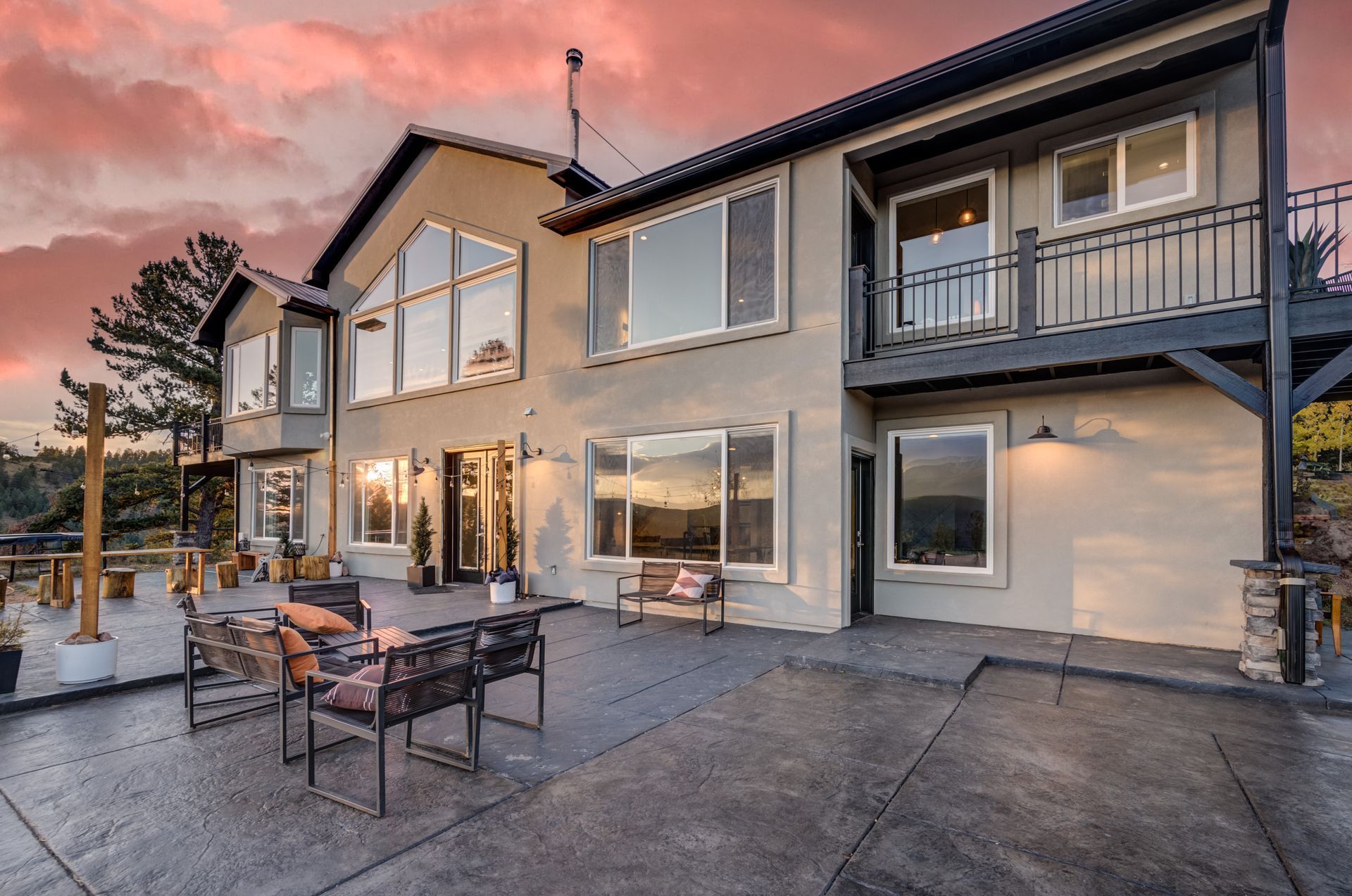 A large house with a lot of windows and a patio with chairs and tables.