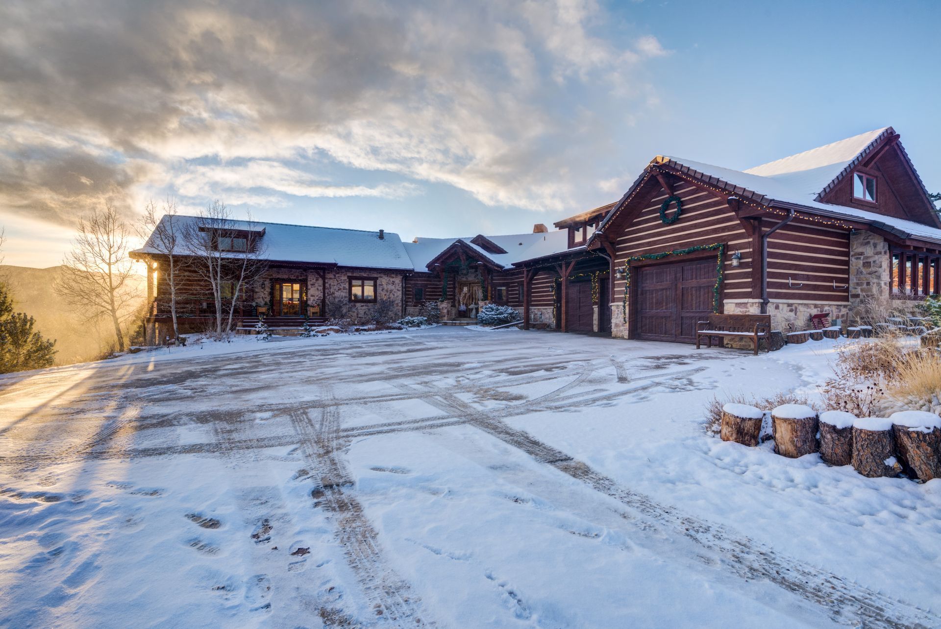 A large log cabin is sitting on top of a snow covered hill.