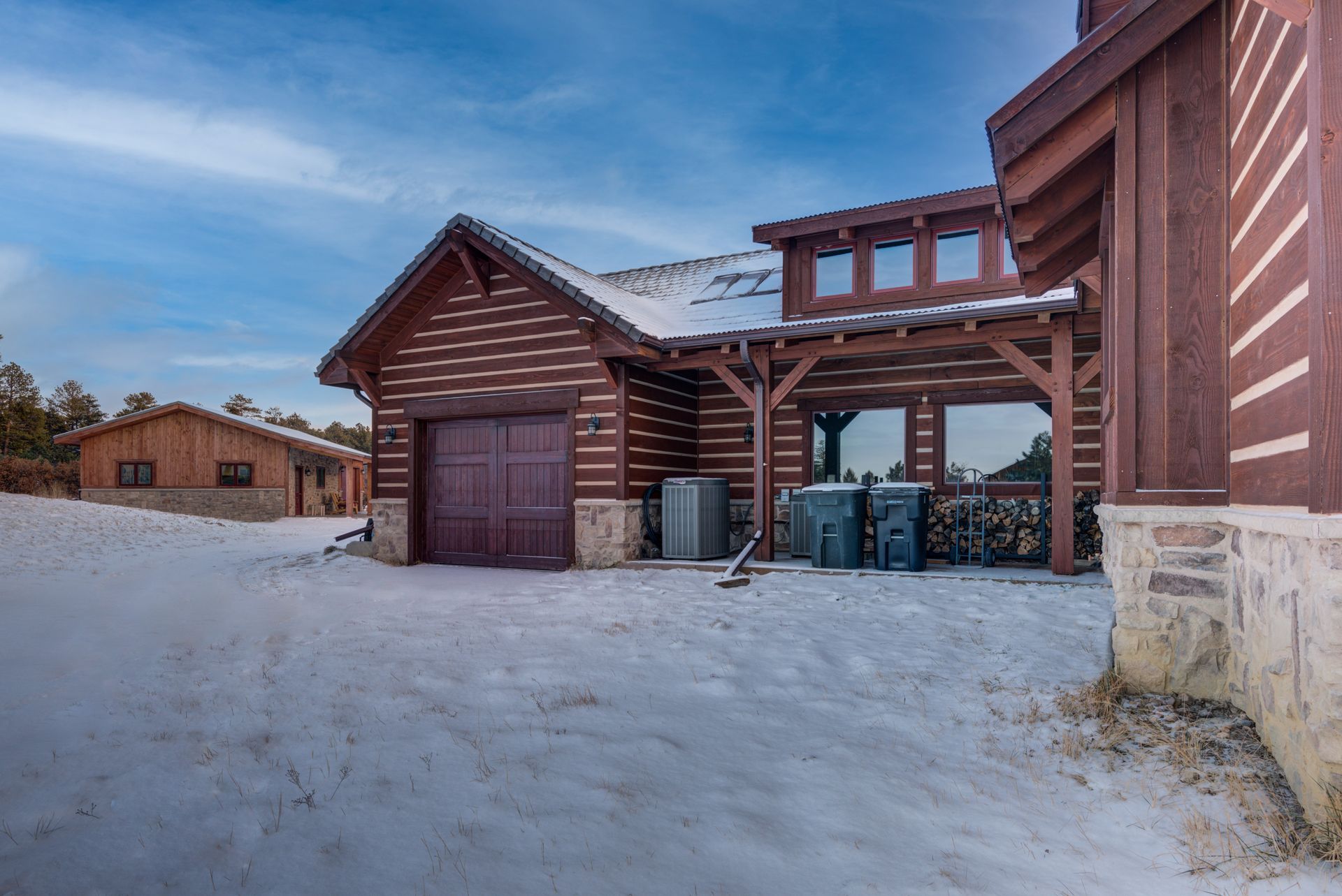 A large log cabin with a garage in the snow.