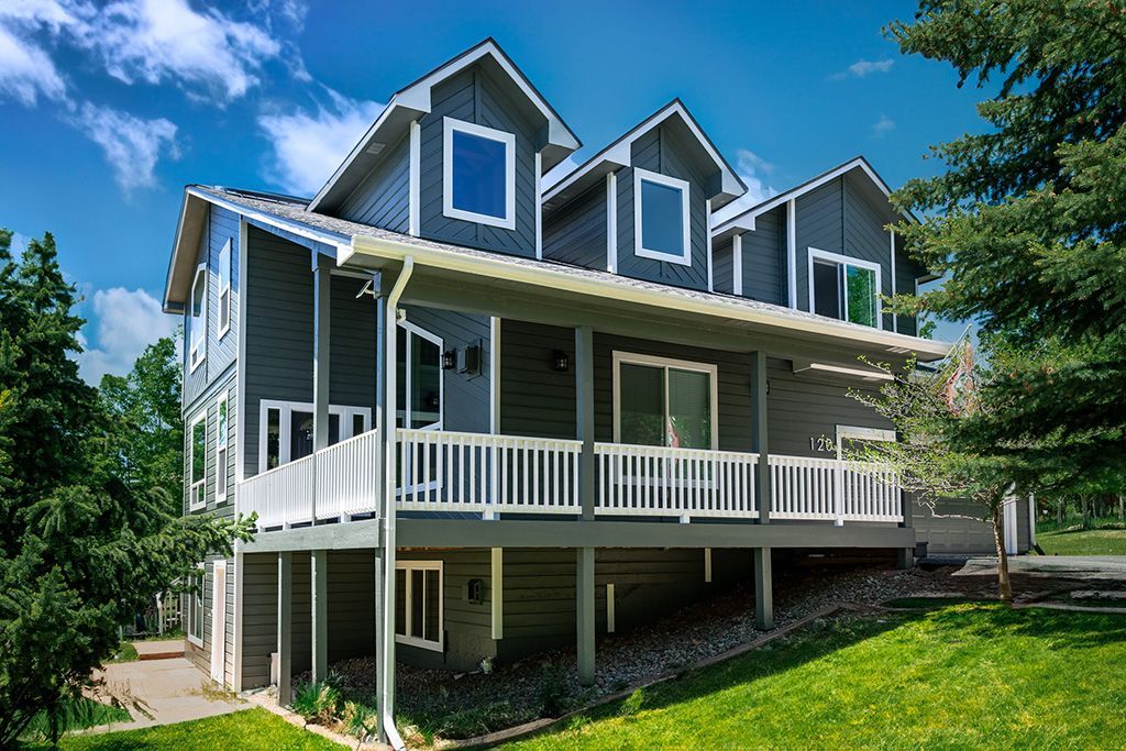 A large house that had a Colorado Springs Exterior Paint Inspection. The house has a lot of windows and balconies is sitting on top of a lush green hillside.