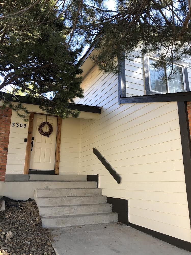 The front of a house with stairs and a wreath on the door.