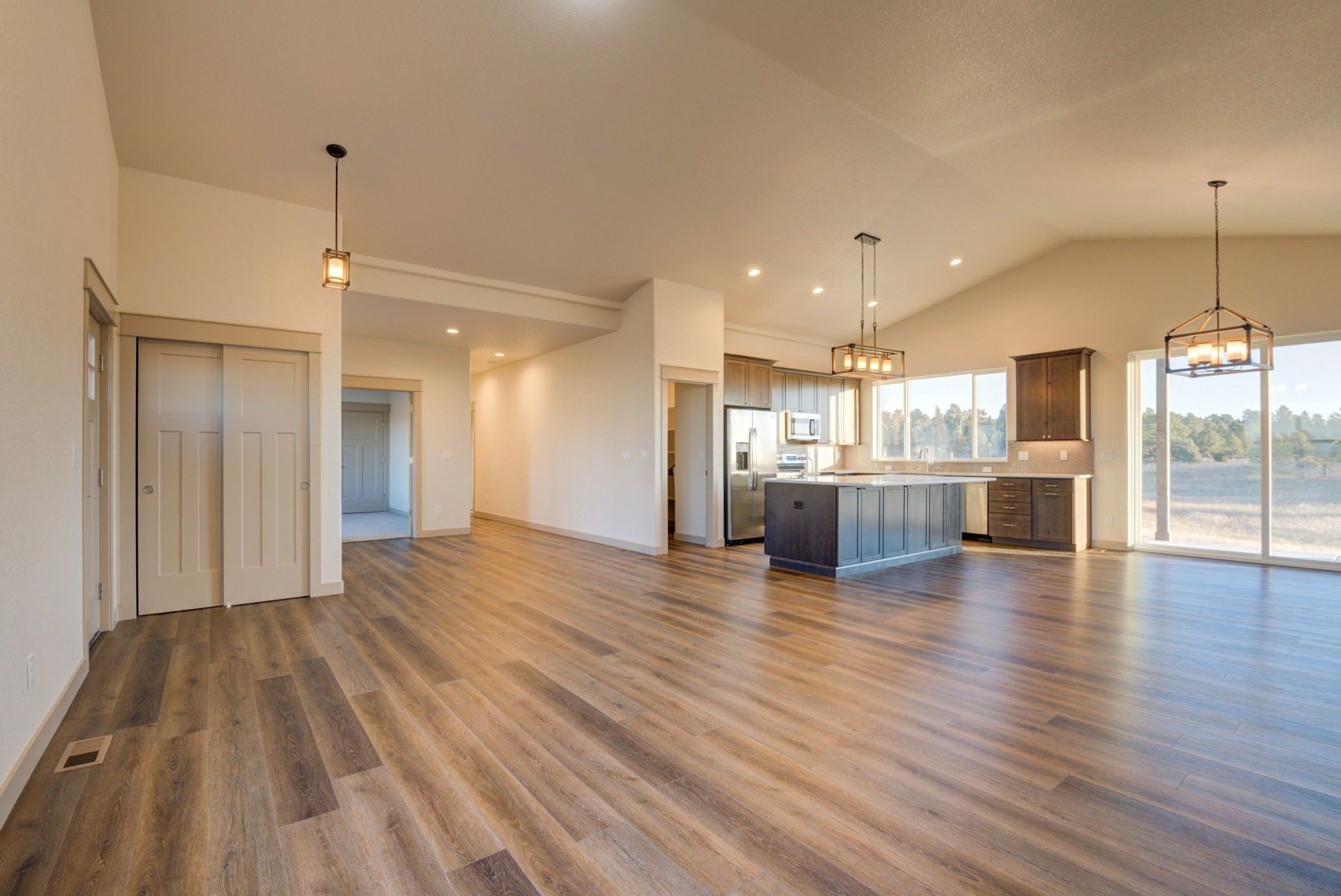 A large empty room with hardwood floors and a kitchen.
