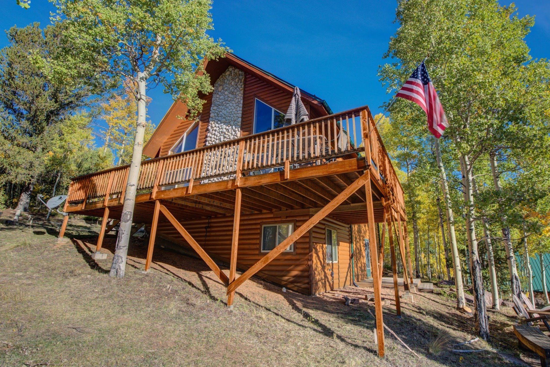 A log cabin with a large deck and an american flag.