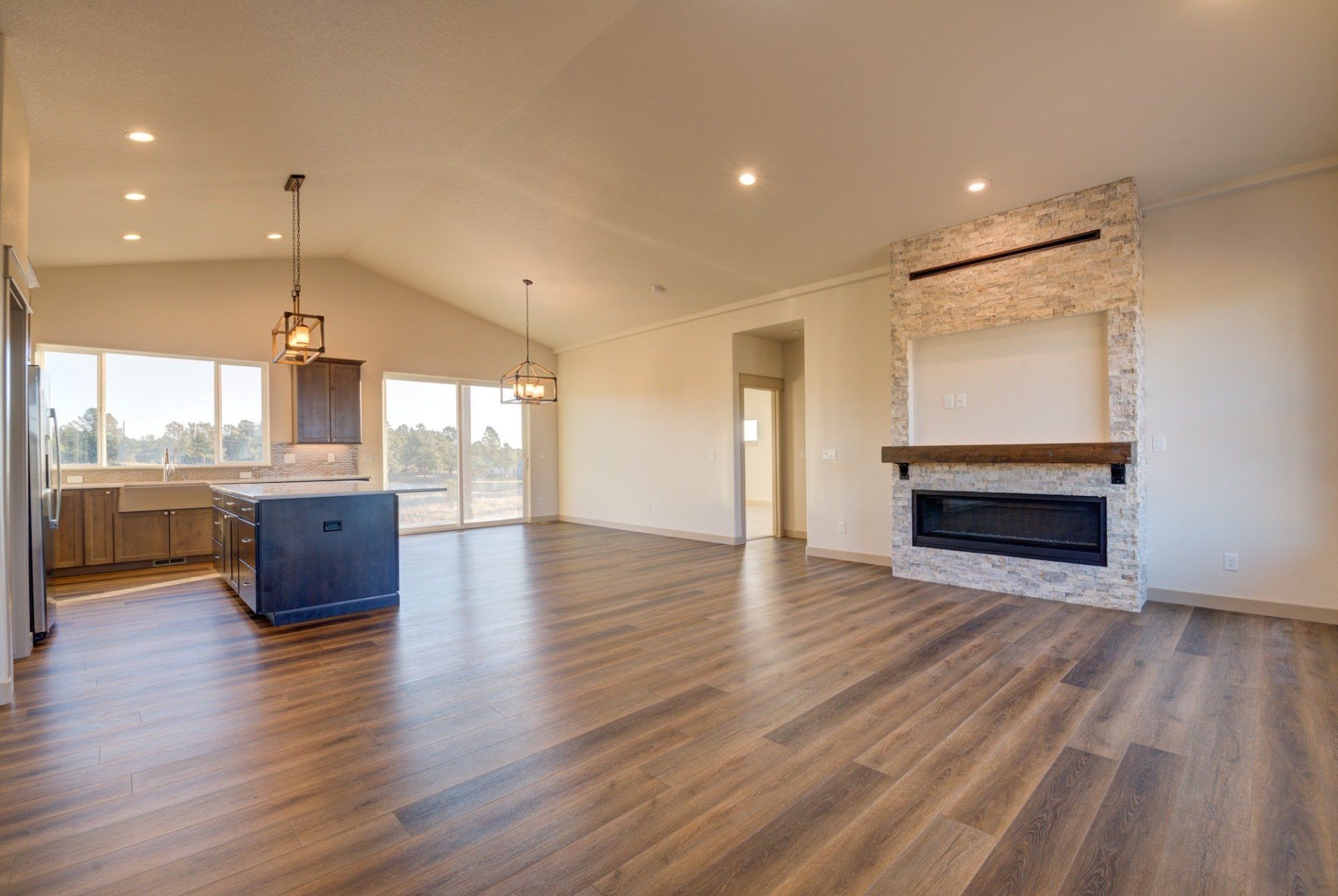 A large empty living room with hardwood floors and a fireplace.