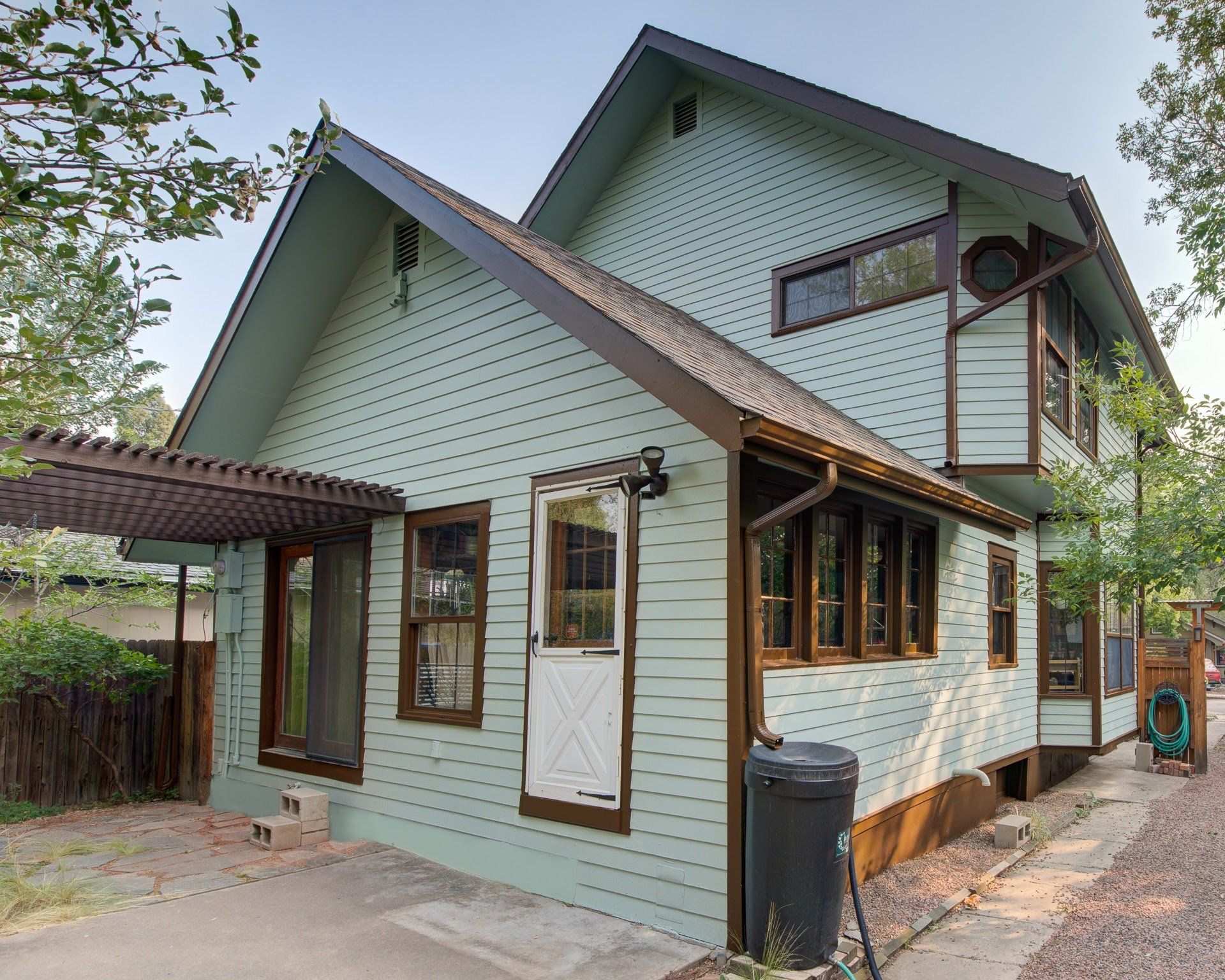 A green house with a brown roof and a lot of windows