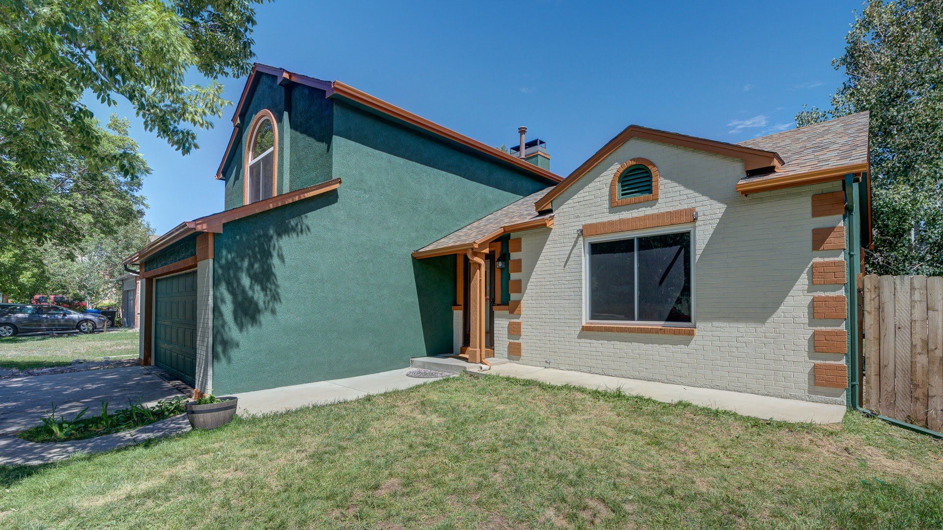 A green house with a brown roof is sitting on top of a lush green lawn.