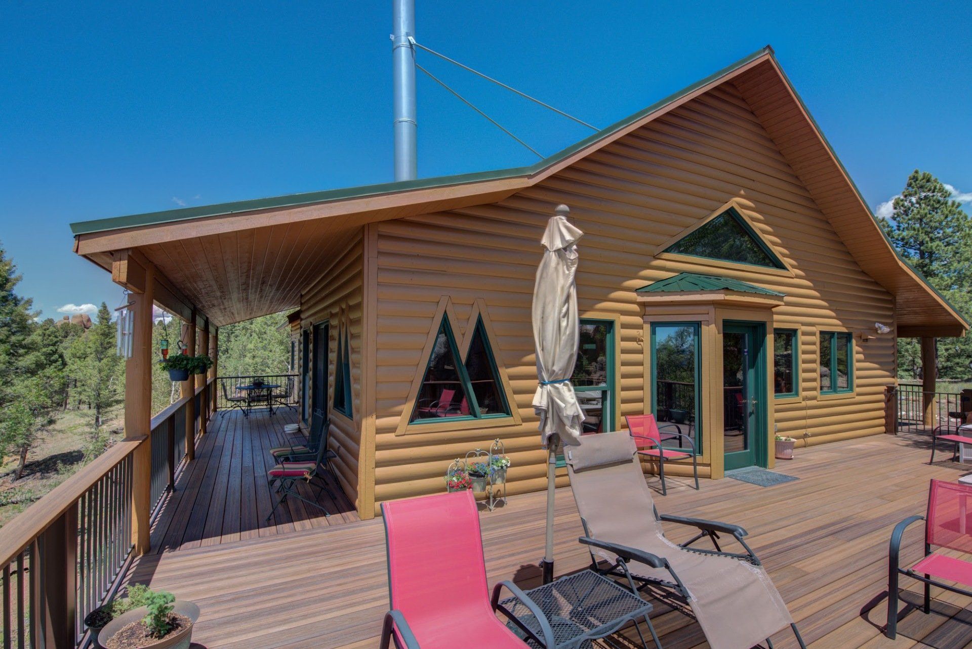 A log cabin with a large deck and chairs on it