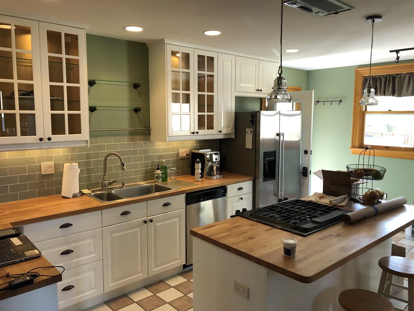 A kitchen with white cabinets , wooden counter tops , stainless steel appliances and a large island.
