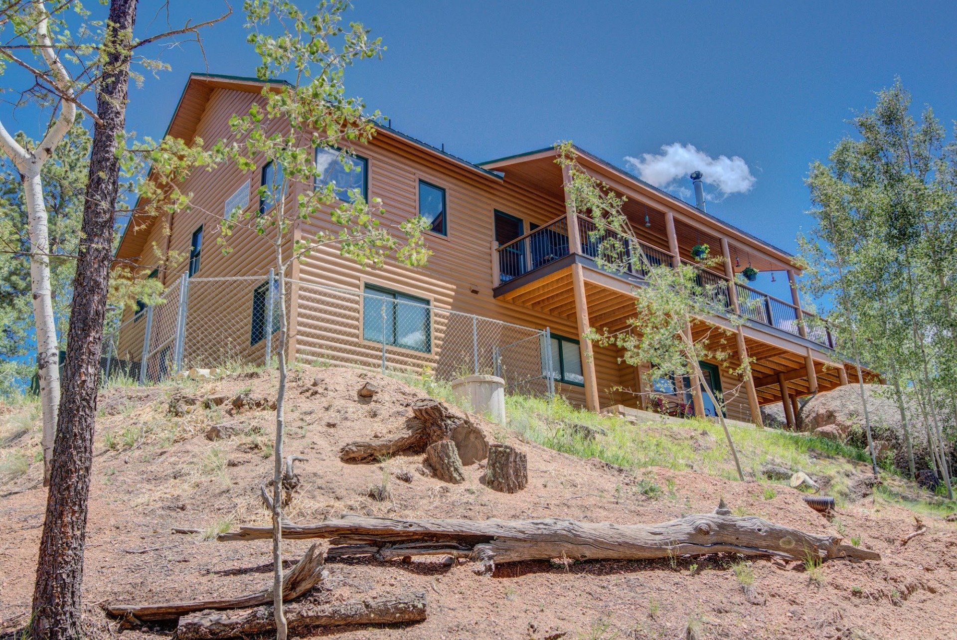 A large wooden house is sitting on top of a hill surrounded by trees.