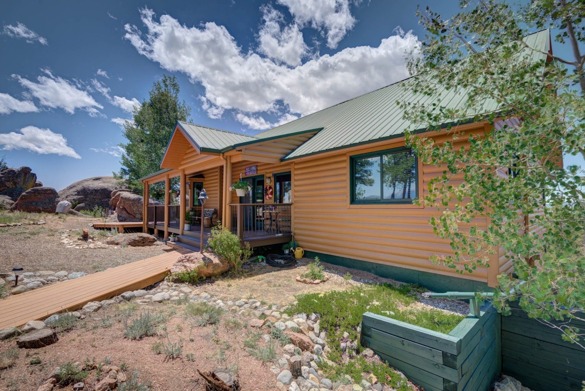 A wooden house with a green roof is sitting on top of a dirt field.
