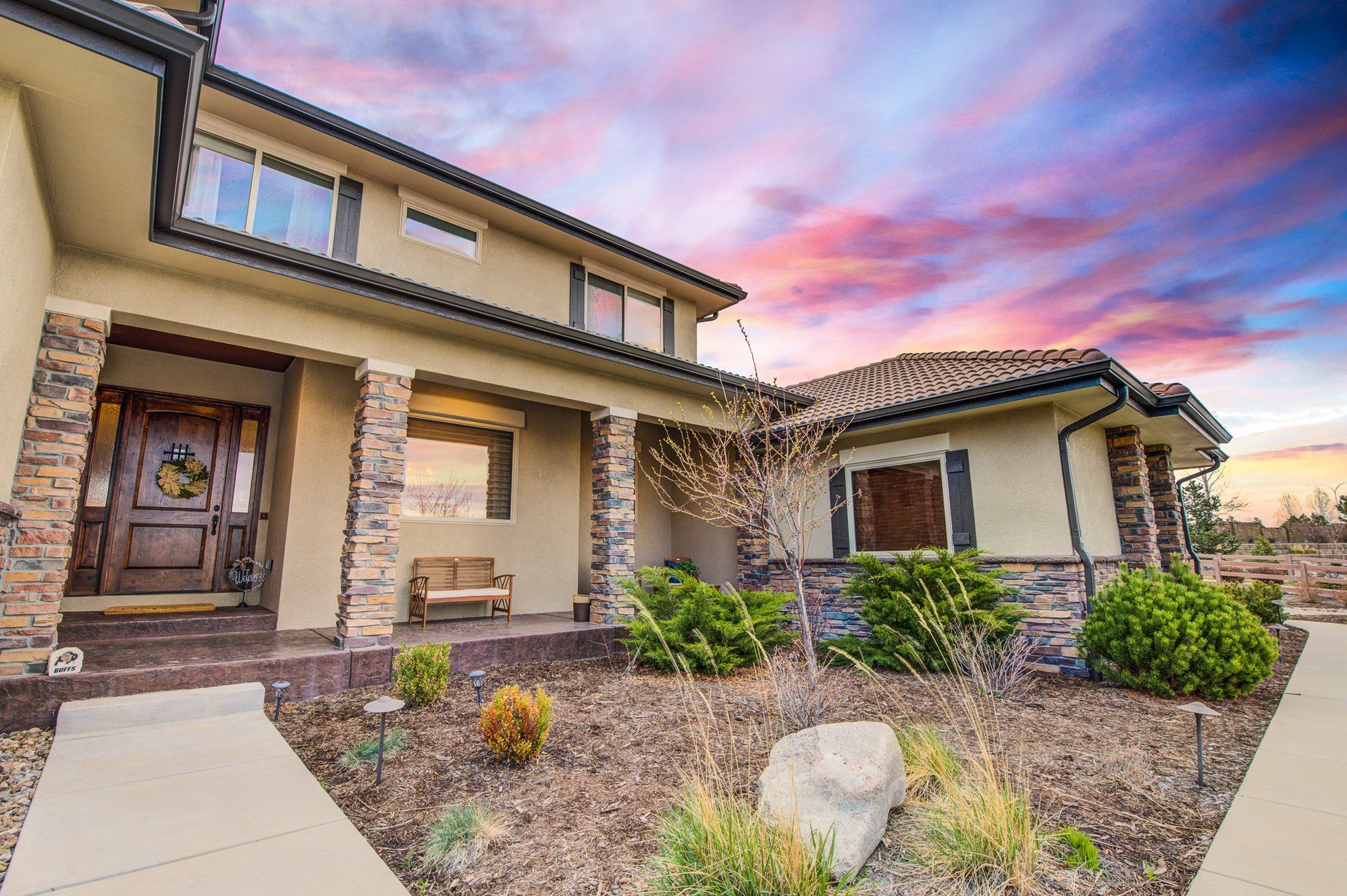 A large house with a large porch and a sunset in the background.