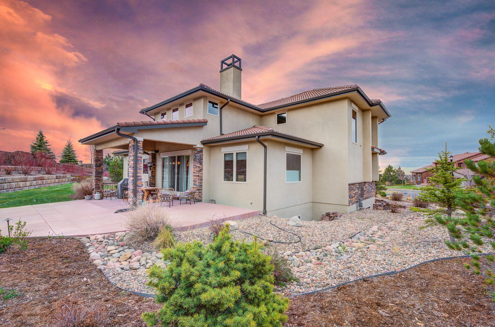 A large house with a patio and a sunset in the background.