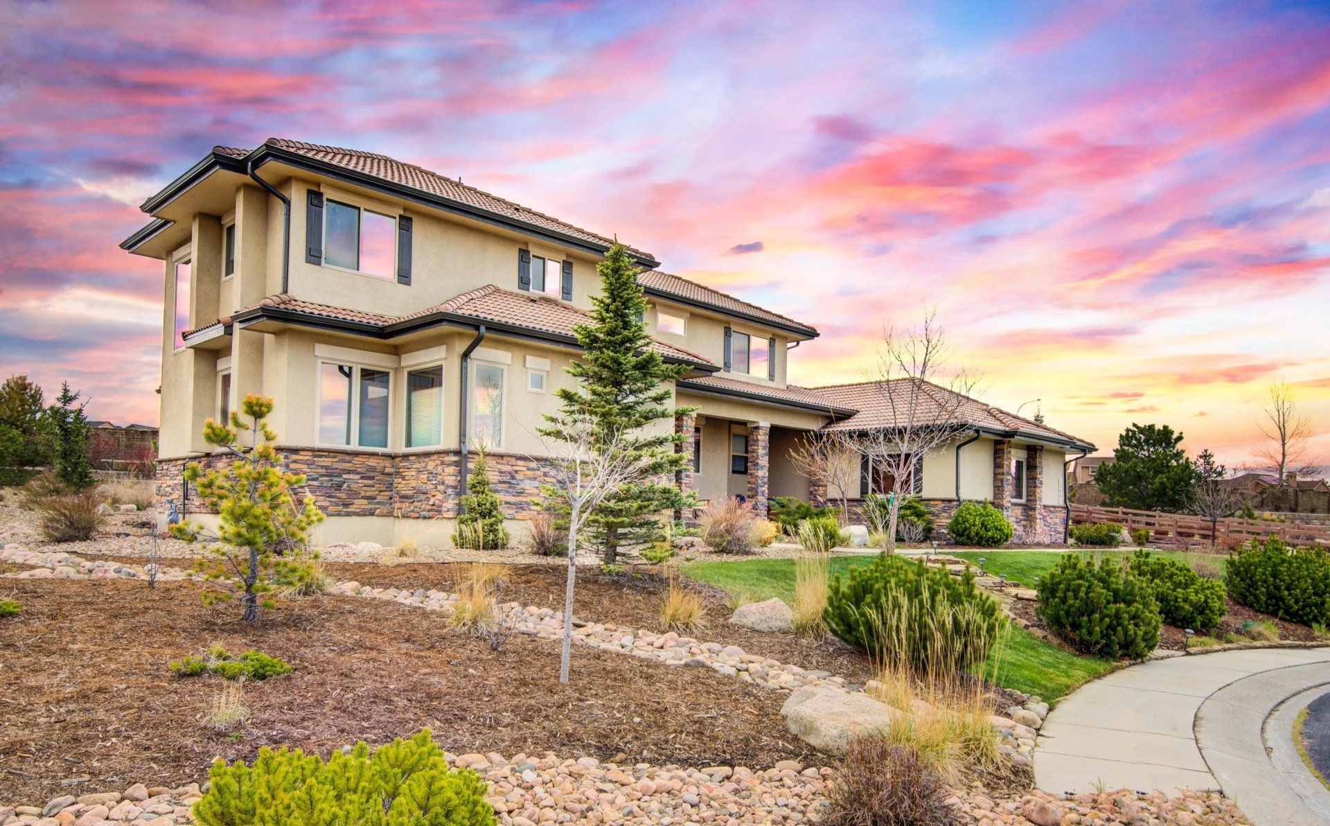 A large house with a lot of windows and a sunset in the background.