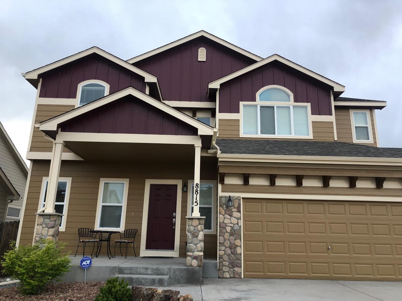 A large house with a purple siding and a brown garage door.