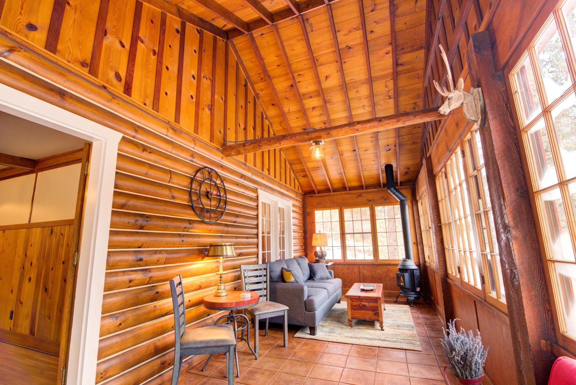 A living room in a log cabin with a couch , table and chairs.