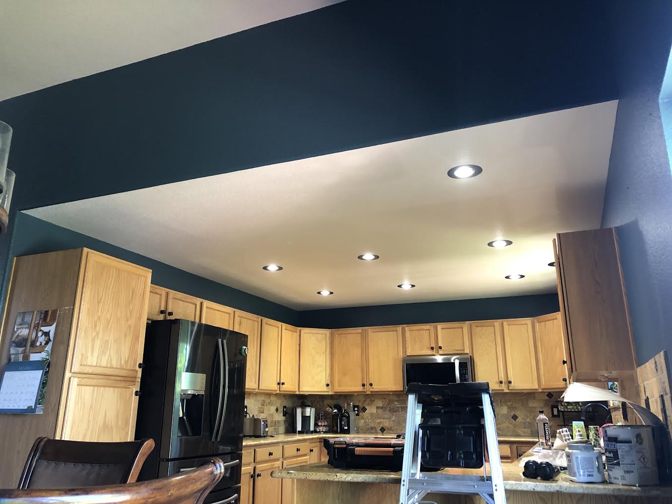A kitchen with wooden cabinets and a black refrigerator.