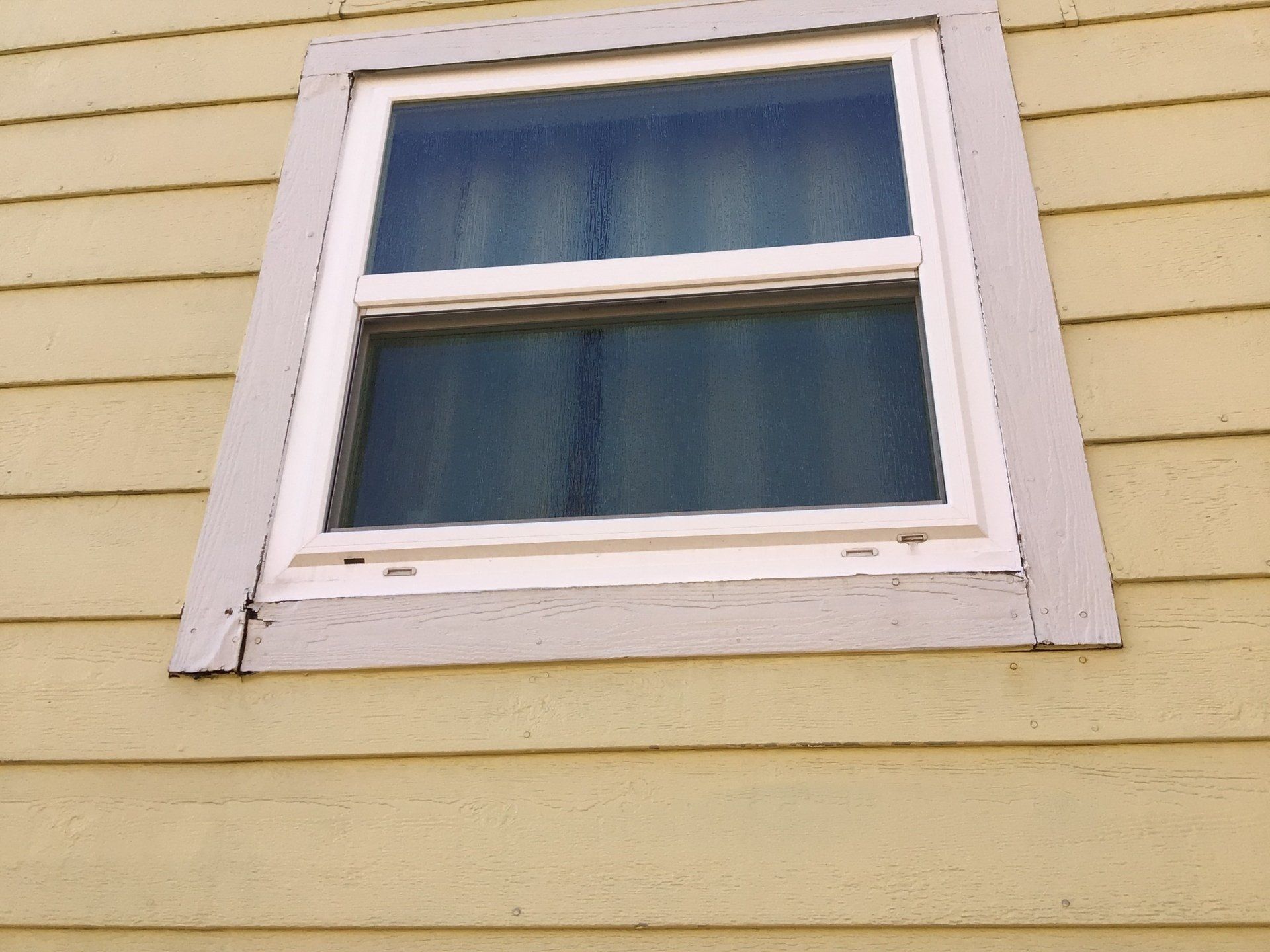 A window on the side of a yellow house