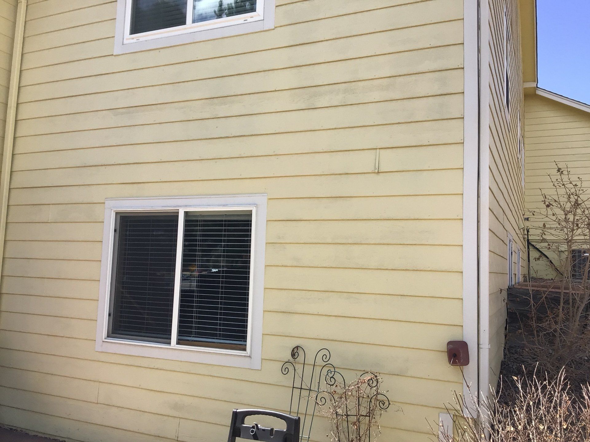 A yellow house with a window and a bench in front of it.
