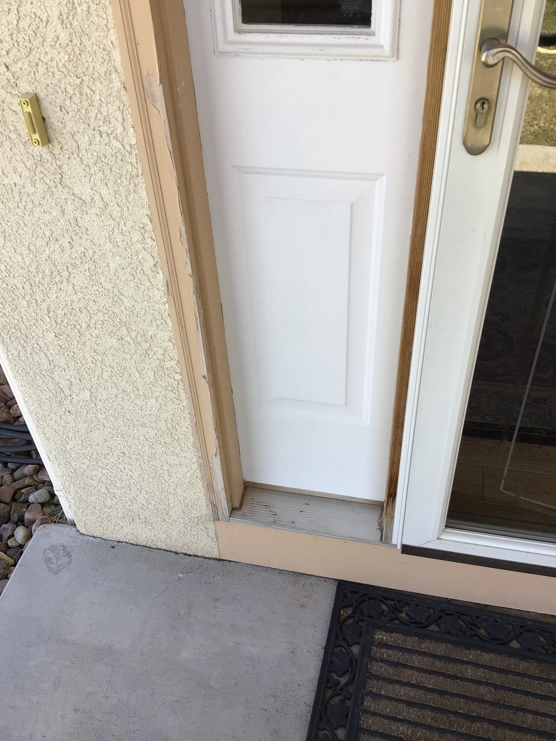 A white door with a window and a black mat on the side of it.