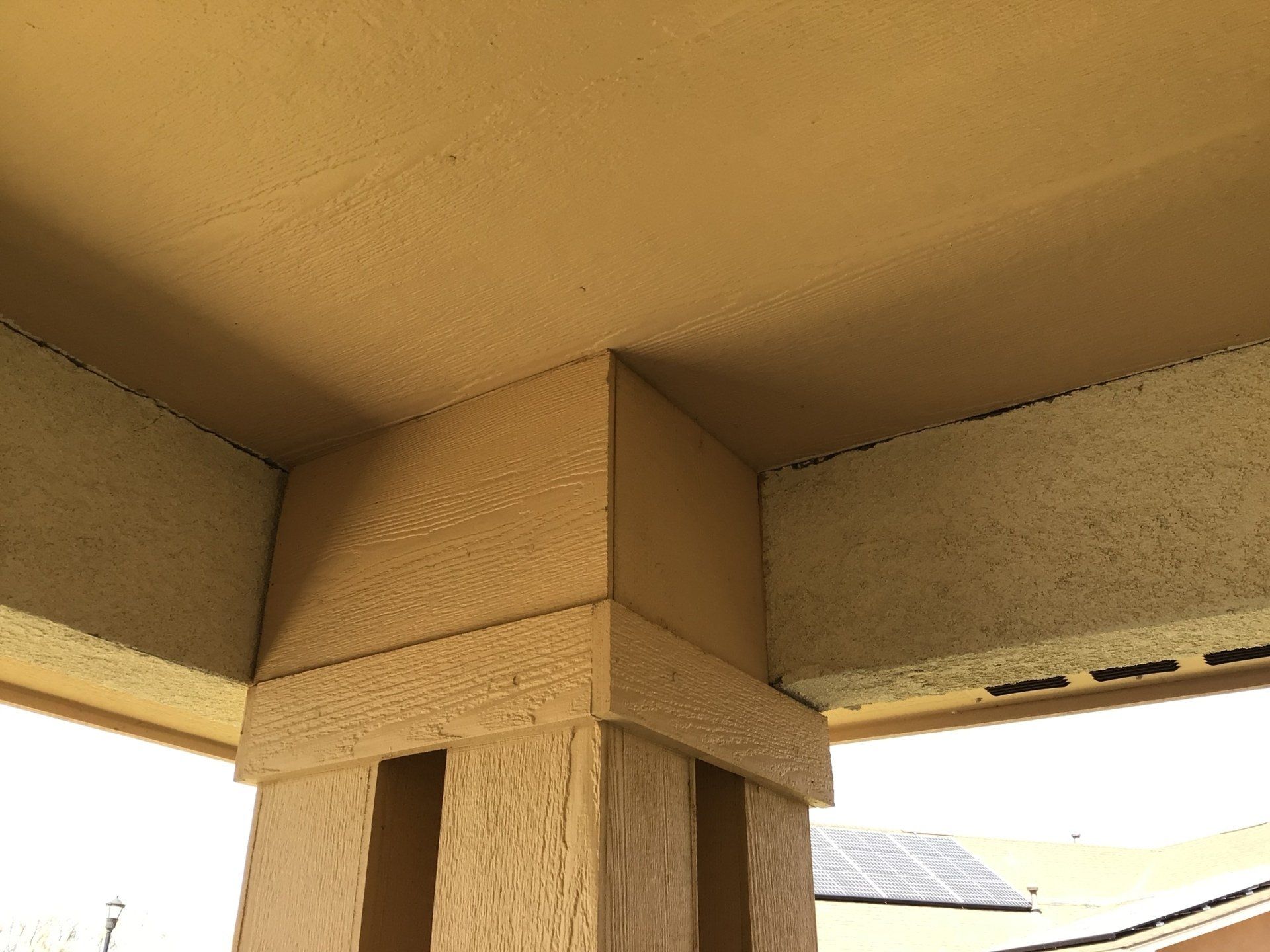 A corner of a building with a ceiling and a pillar.
