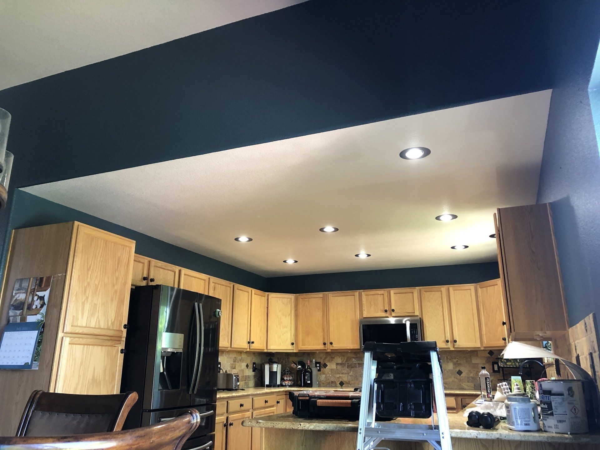 A kitchen with wooden cabinets and a black refrigerator.