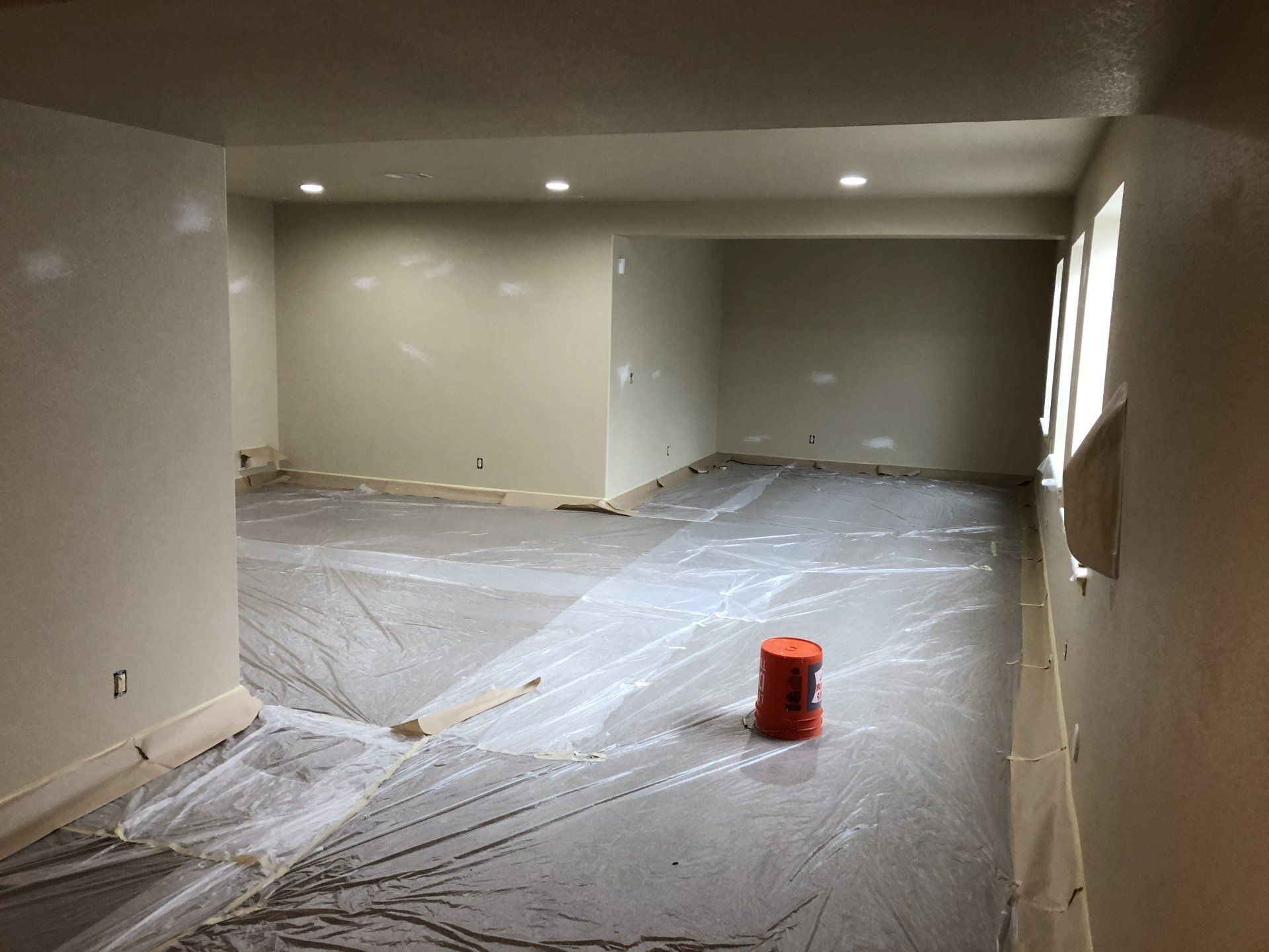 A room with white walls and a red bucket on the floor.