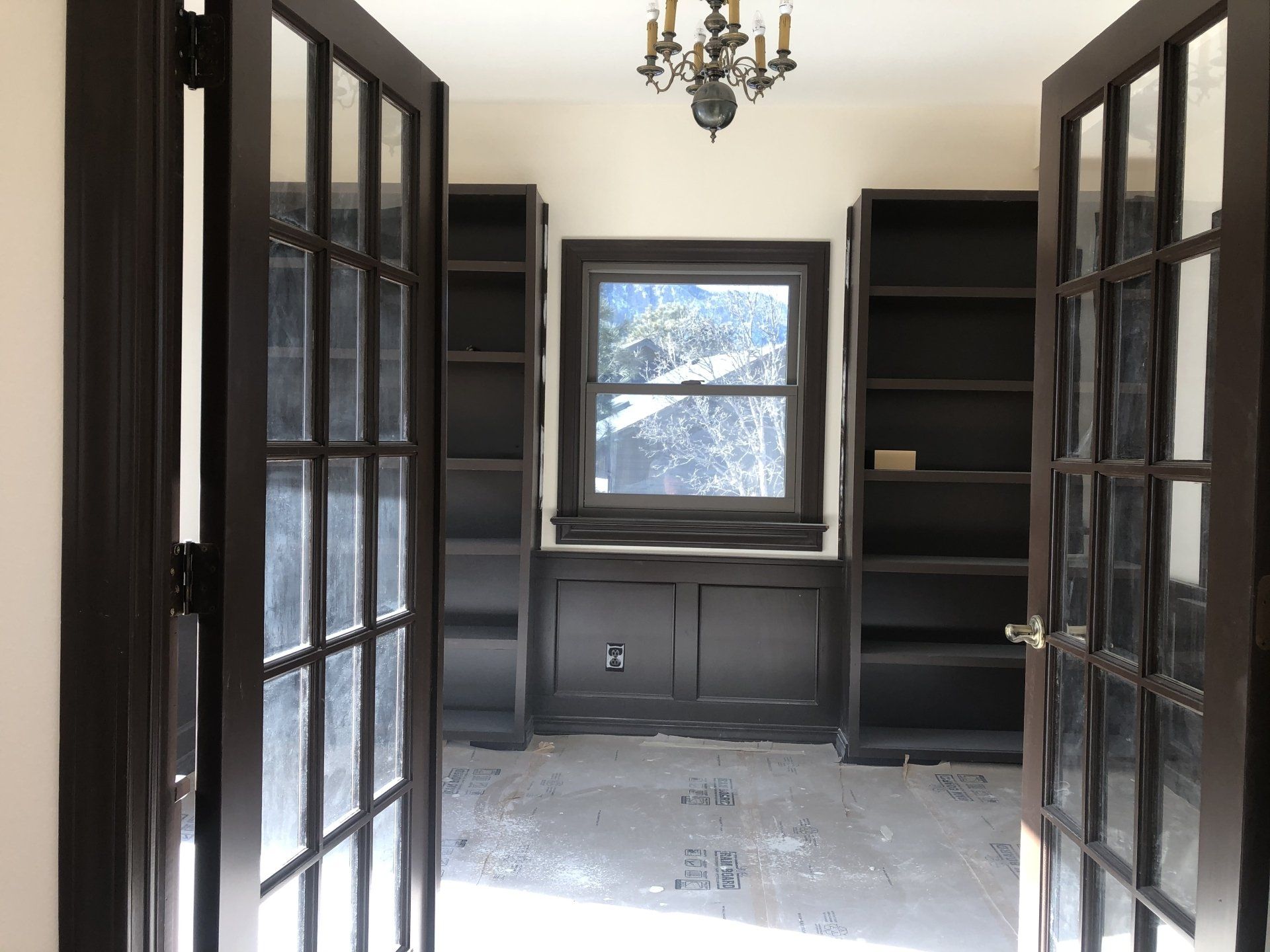 An empty room with french doors and shelves and a window