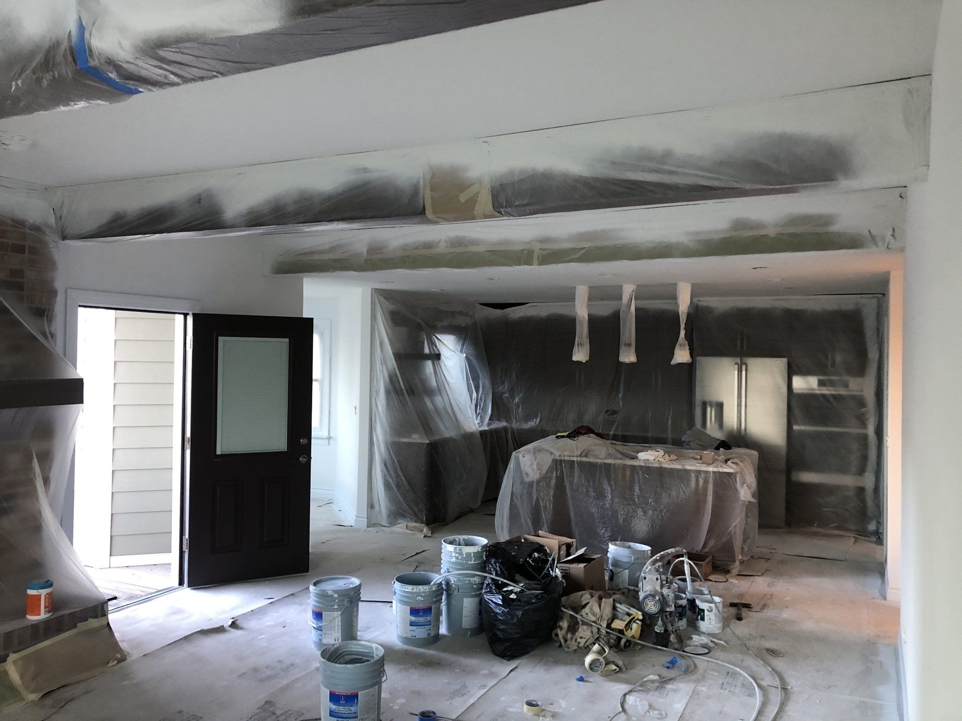 A room that is being painted with buckets of paint on the floor.