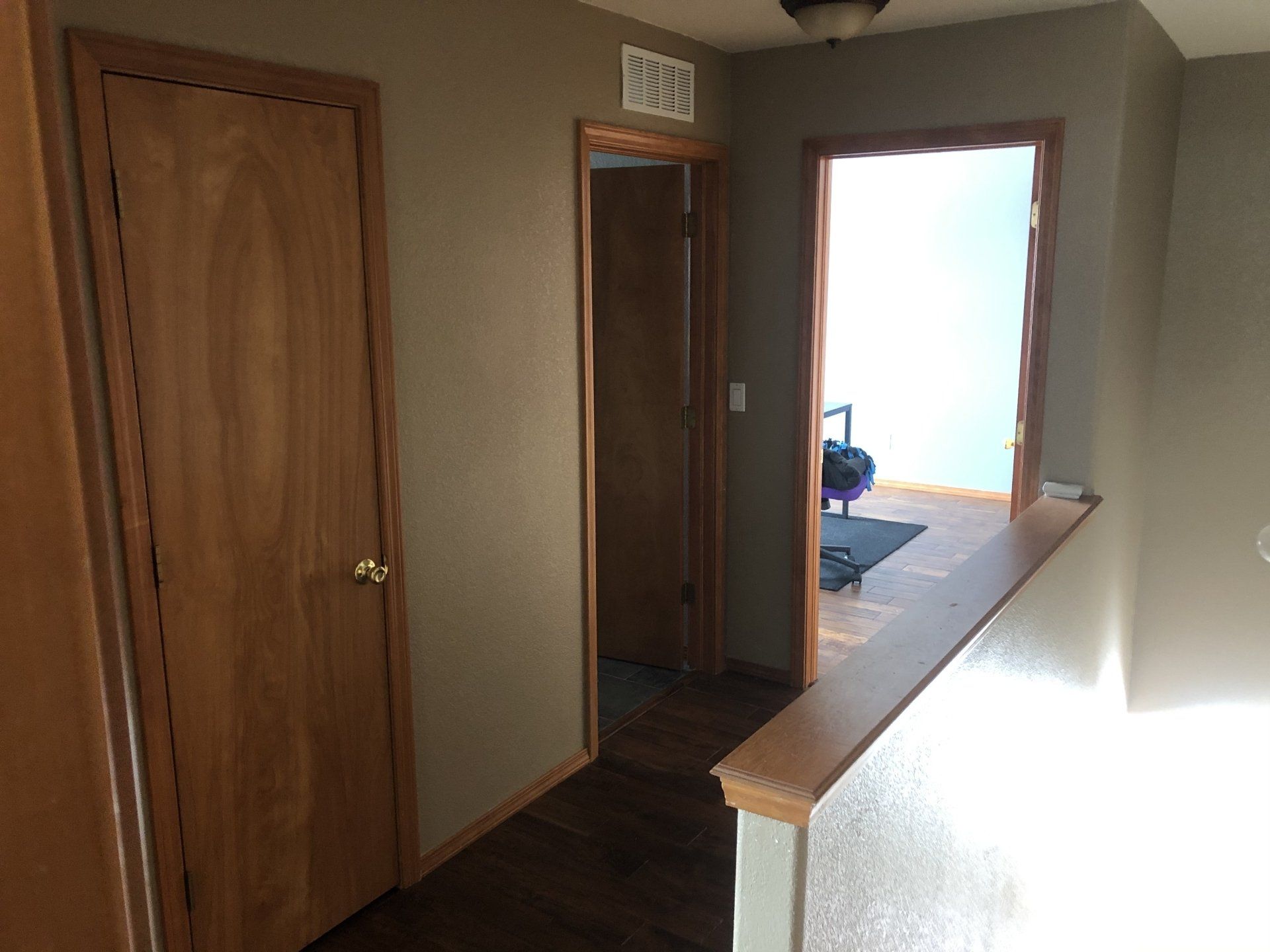 A hallway with wooden doors and a staircase in a house.