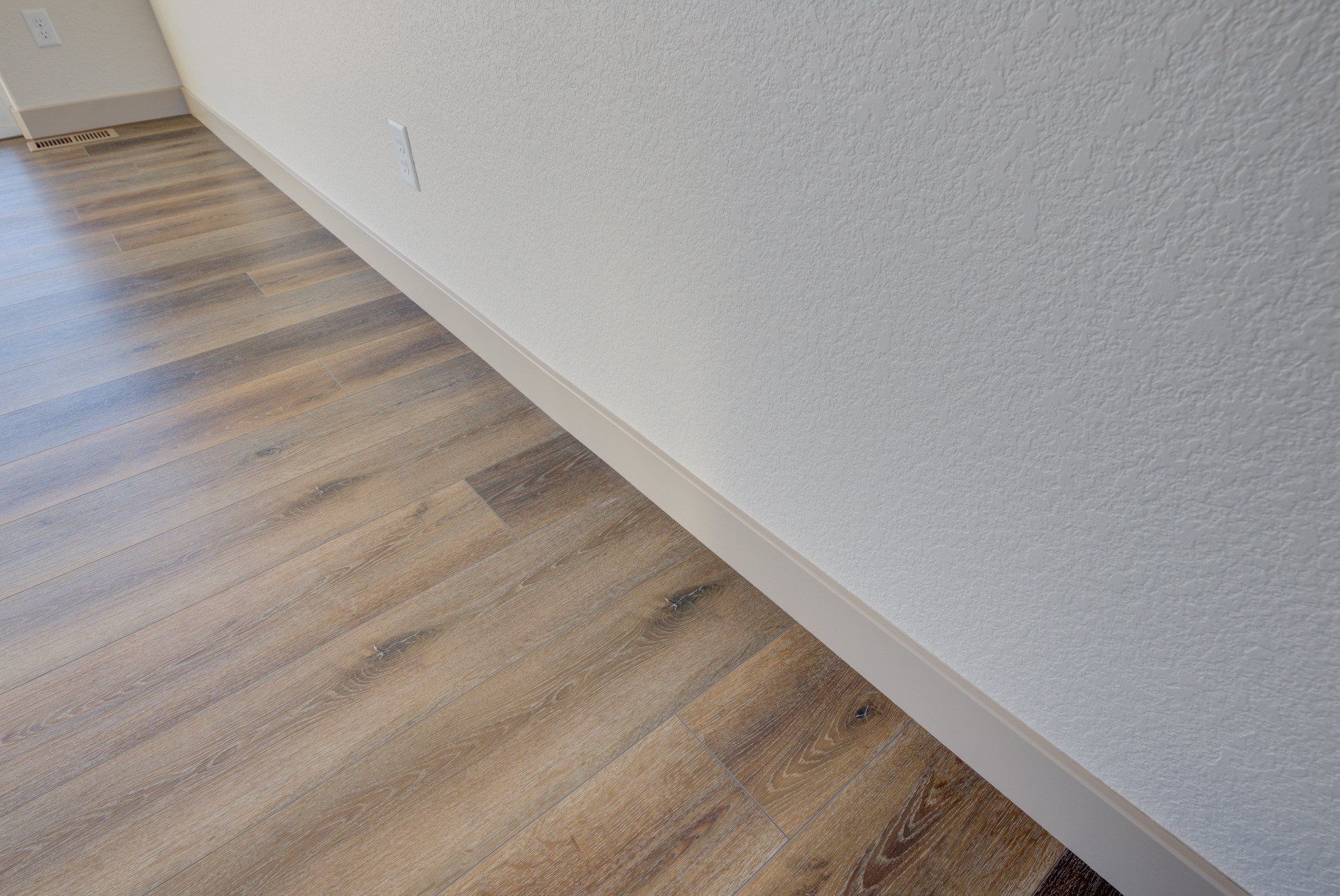 A room with a wooden floor and a white wall.