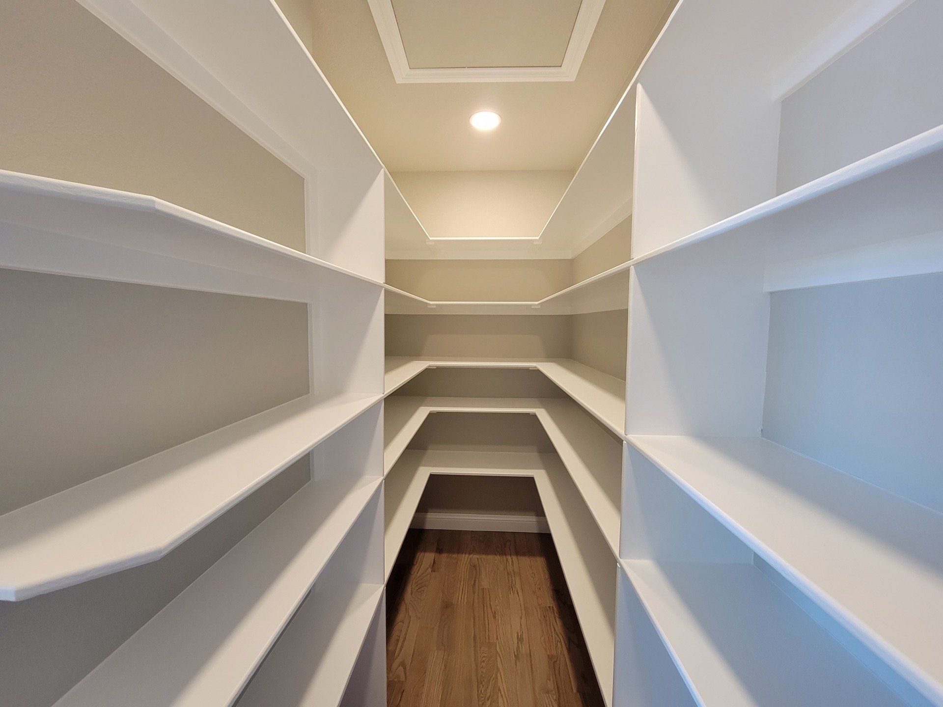 A narrow walk in pantry with lots of shelves
