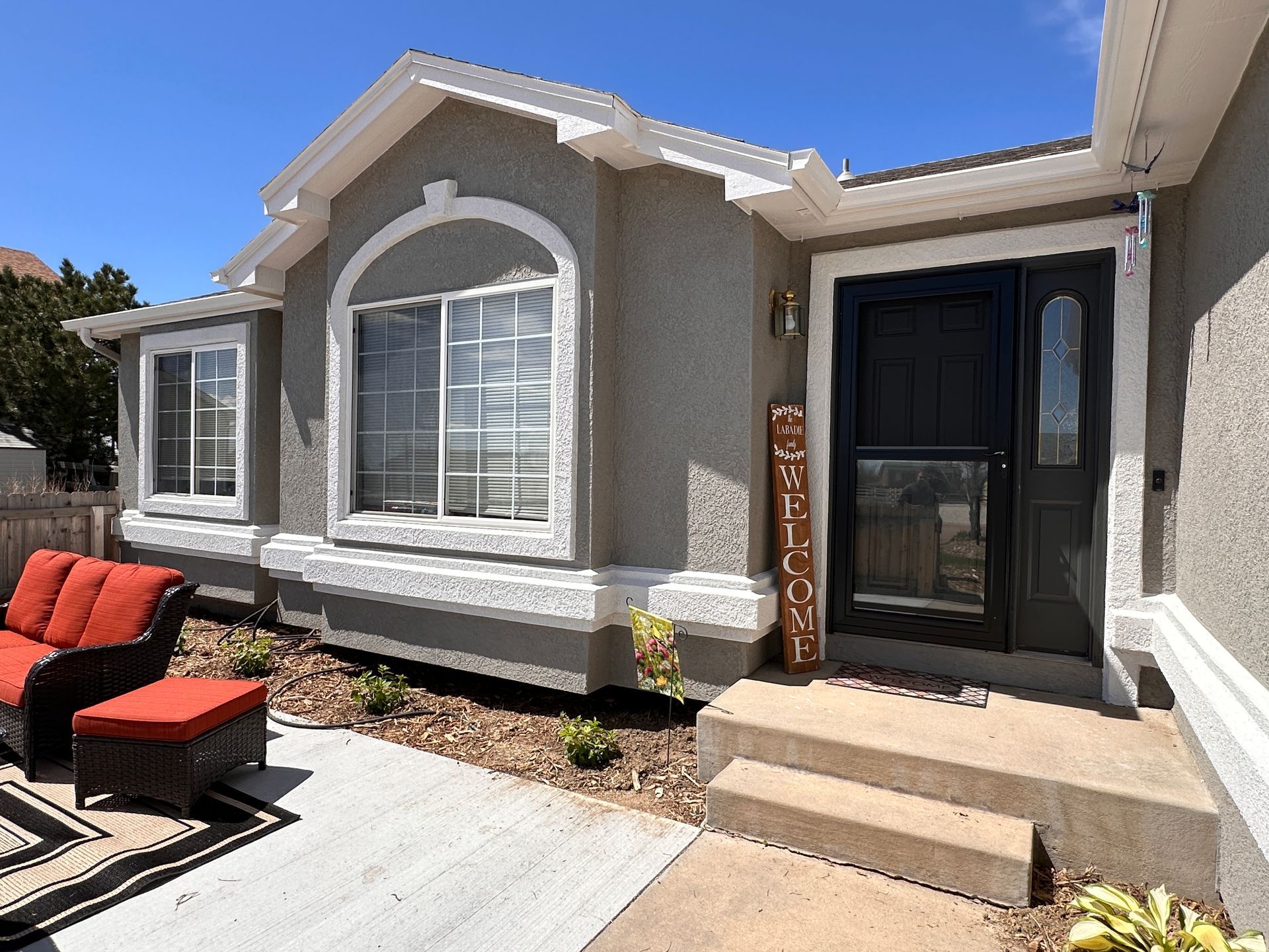 A nicely painted gray house in Colorado Springs with a black door and steps