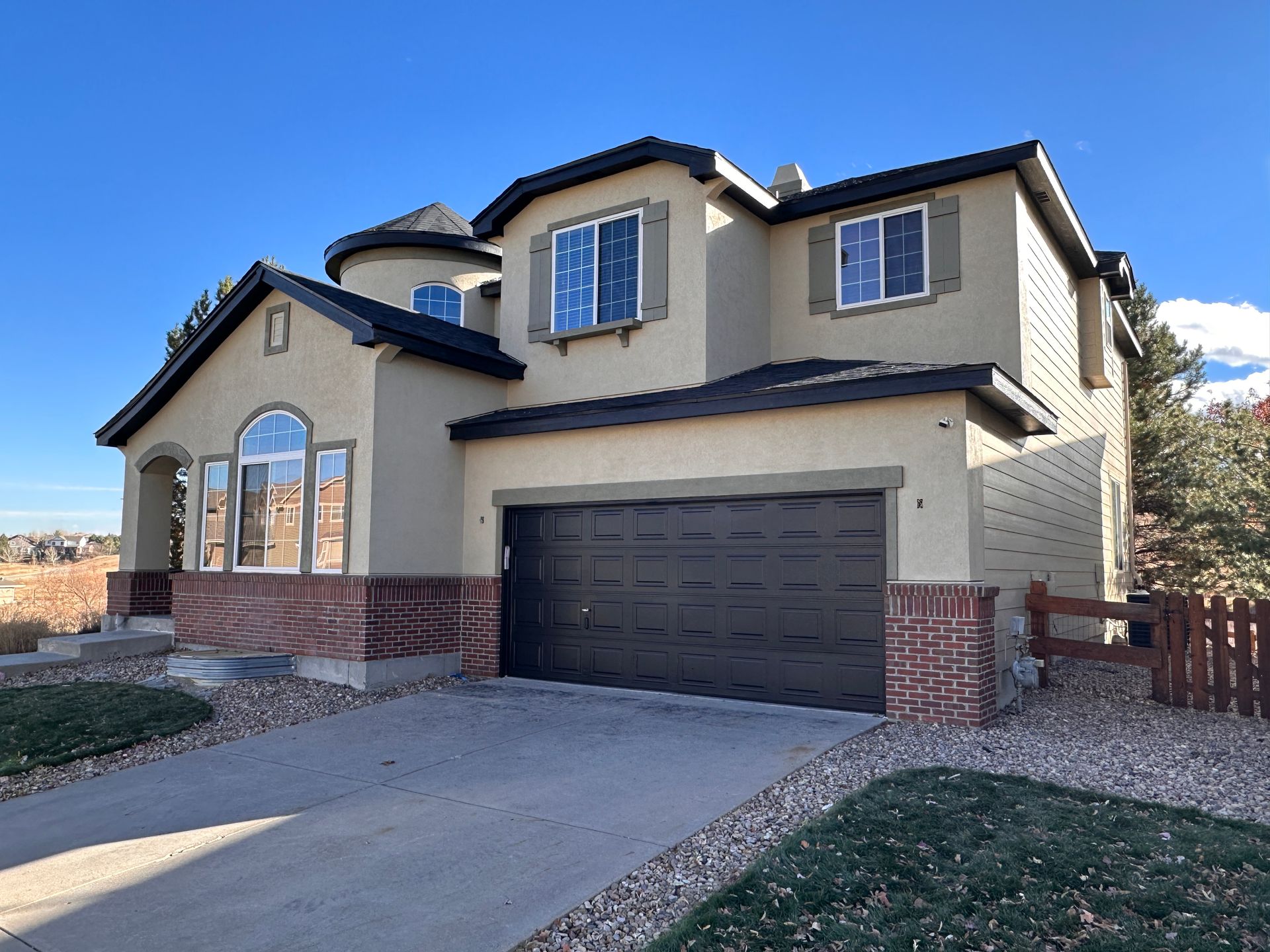 A large painted stucco house with a large garage and a lot of windows