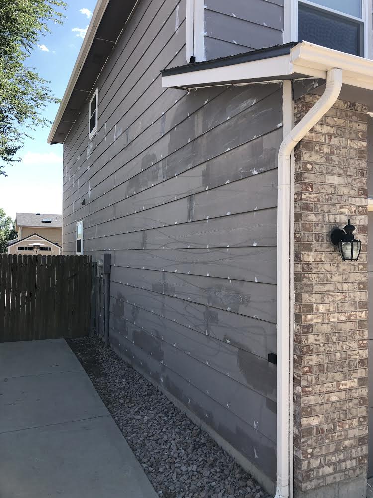 A house with a brick wall and a gutter on the side of it.