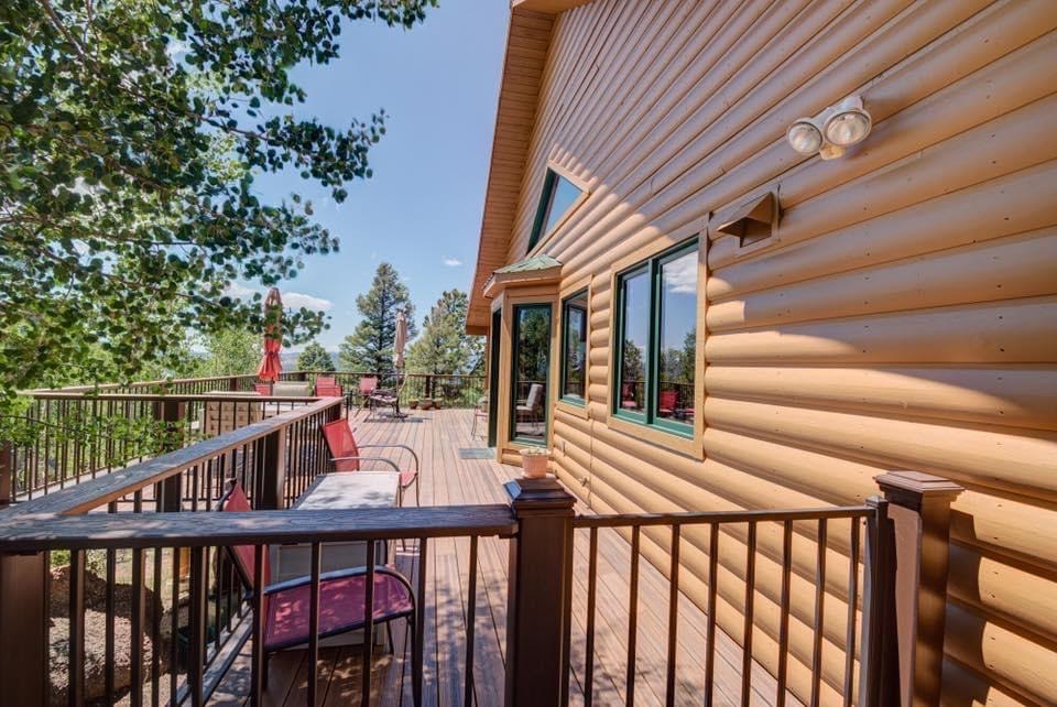 A log cabin with a large deck and a fence around it.