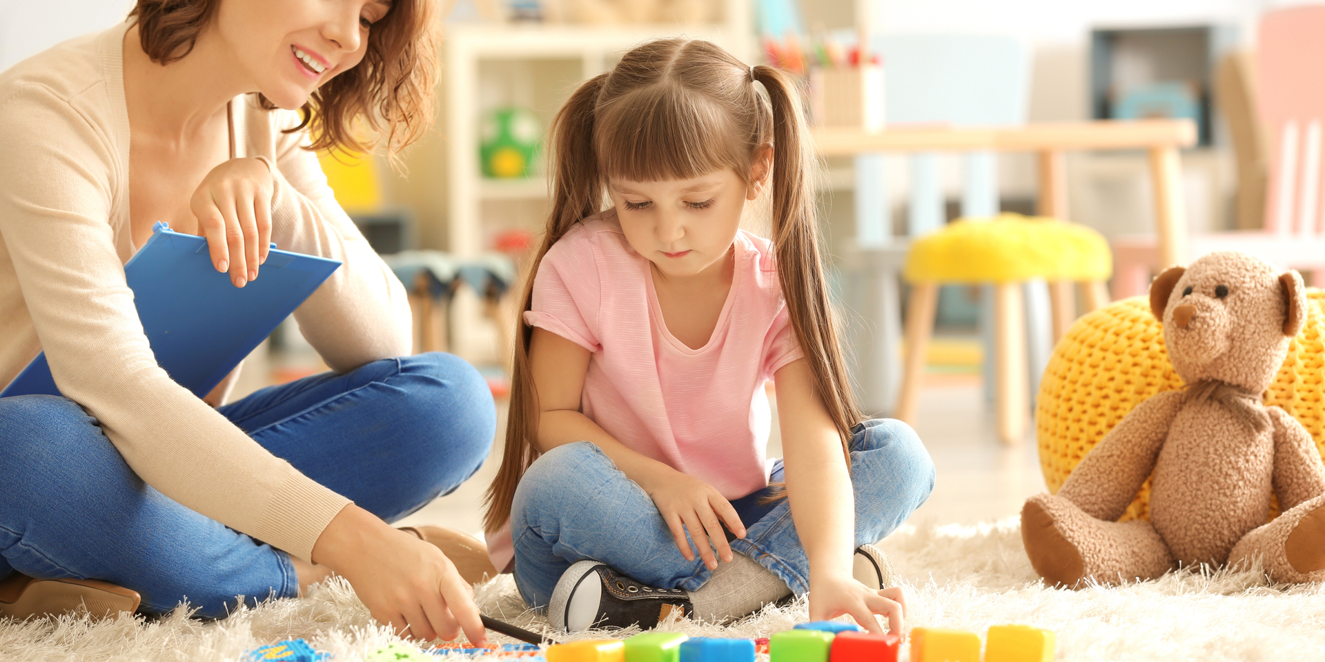 A teacher sits with two parents and a student at a table in a classroom.