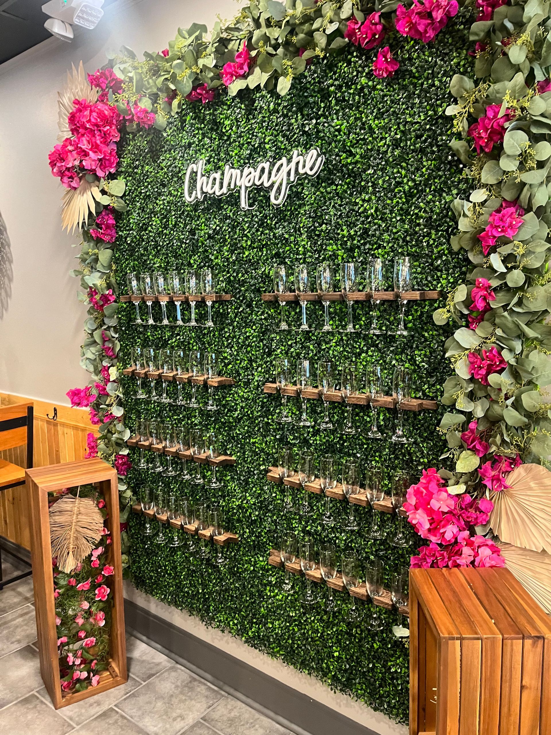 A wall filled with champagne glasses and pink flowers.