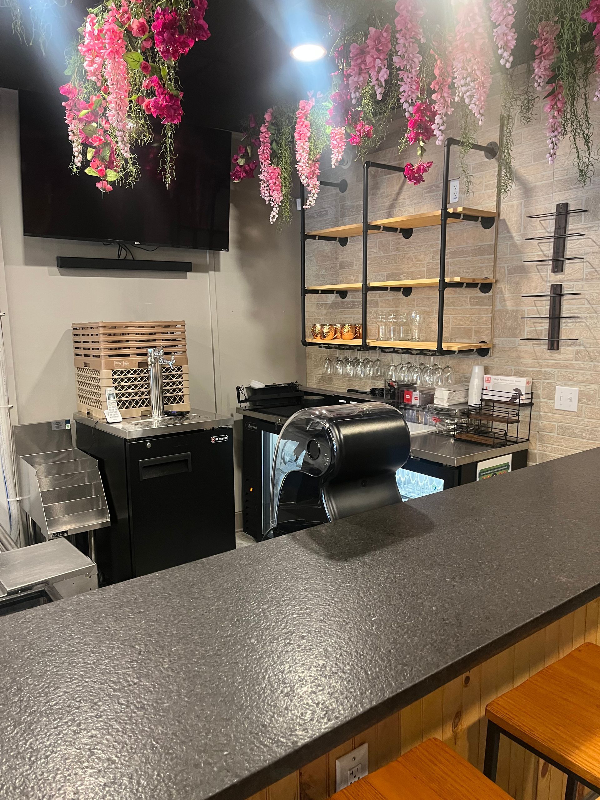 A kitchen with a long counter and flowers hanging from the ceiling.