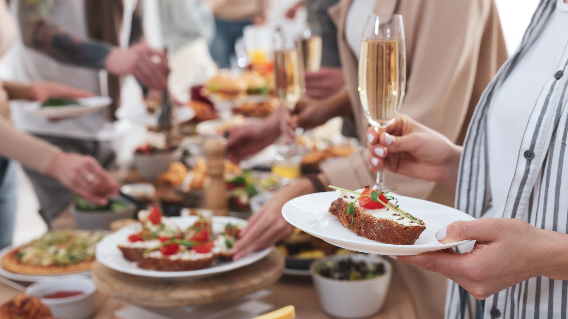 a woman is holding a plate of food and a glass of champagne .