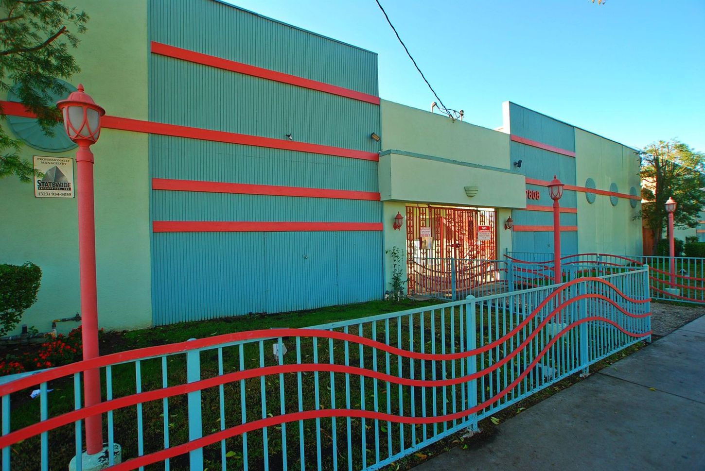 Exterior of building with light blue and red accents. Red wave-patterned fence.