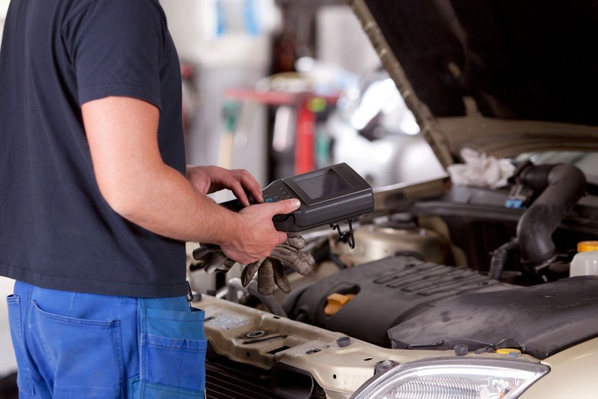 A man is standing in front of a car with the hood open. | Eden Automotive Repair