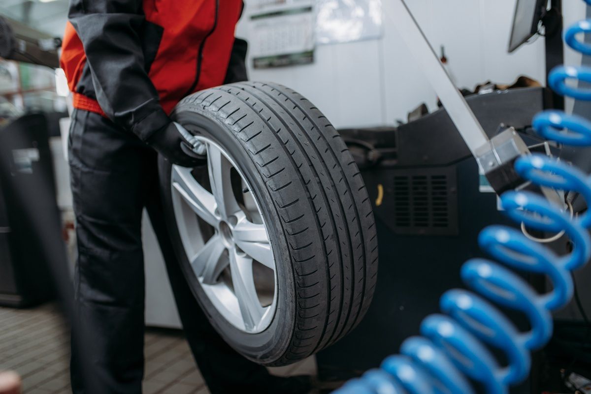 A man is balancing a tire on a machine in a garage. | Eden Automotive Repair