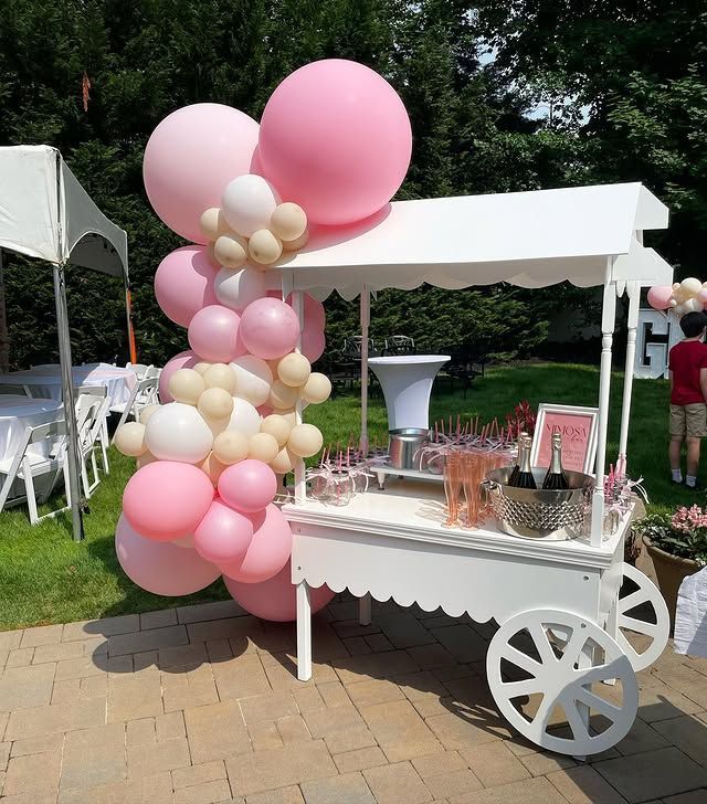 A cart with pink and white balloons on it