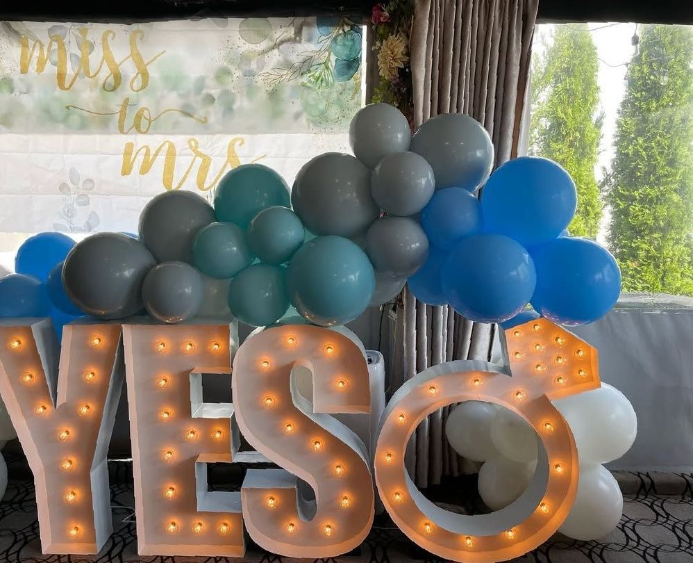 A sign that says yes is surrounded by balloons.