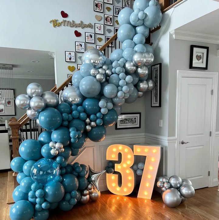 A staircase decorated with blue and silver balloons and a lighted number 37