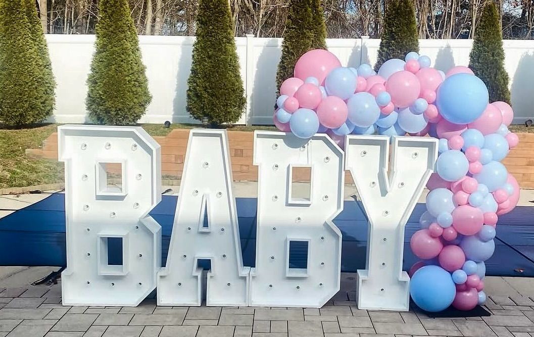 The word baby is surrounded by pink and blue balloons.